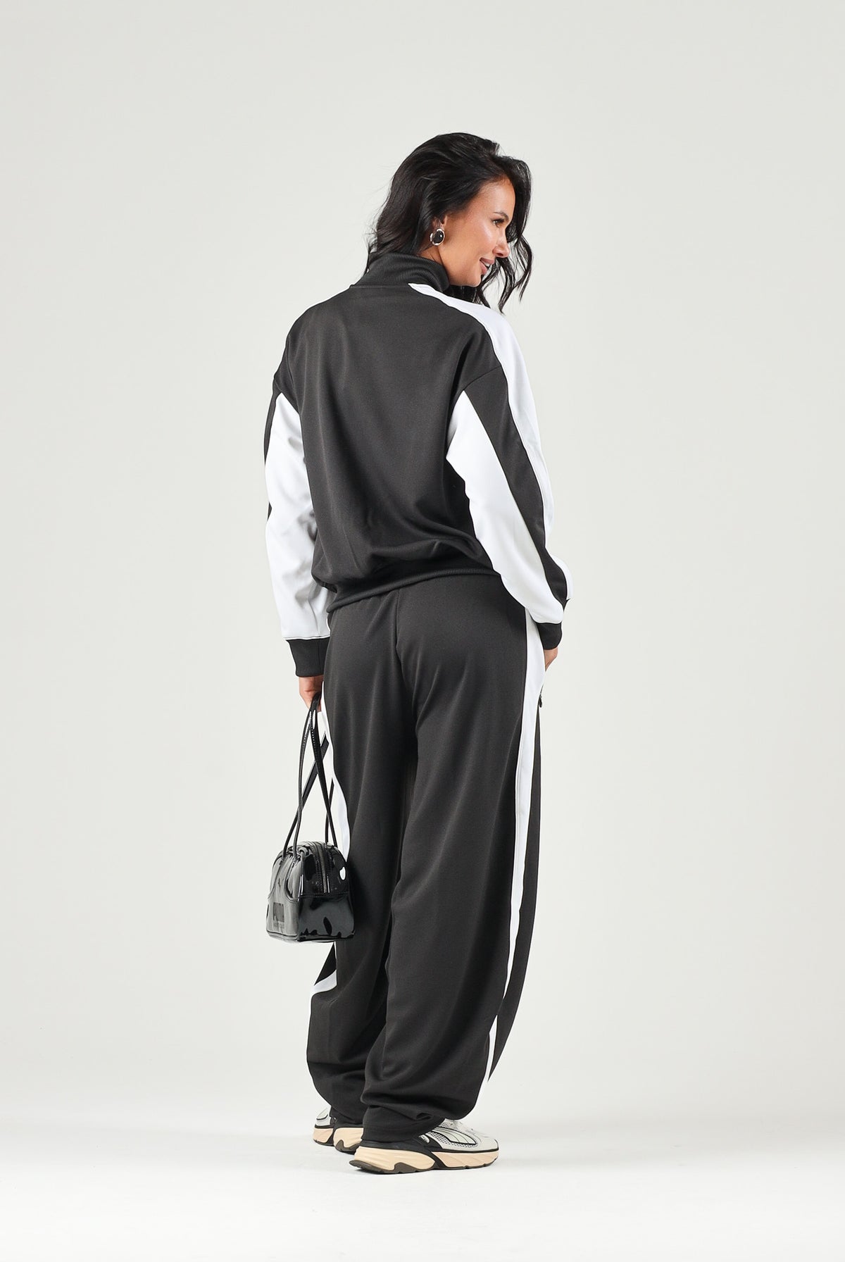 PUMA Pantalone DARE TO WOVEN nero per donna con bande laterali bianche, tasche zippate e gamba ampia. 636633 01 PUMA