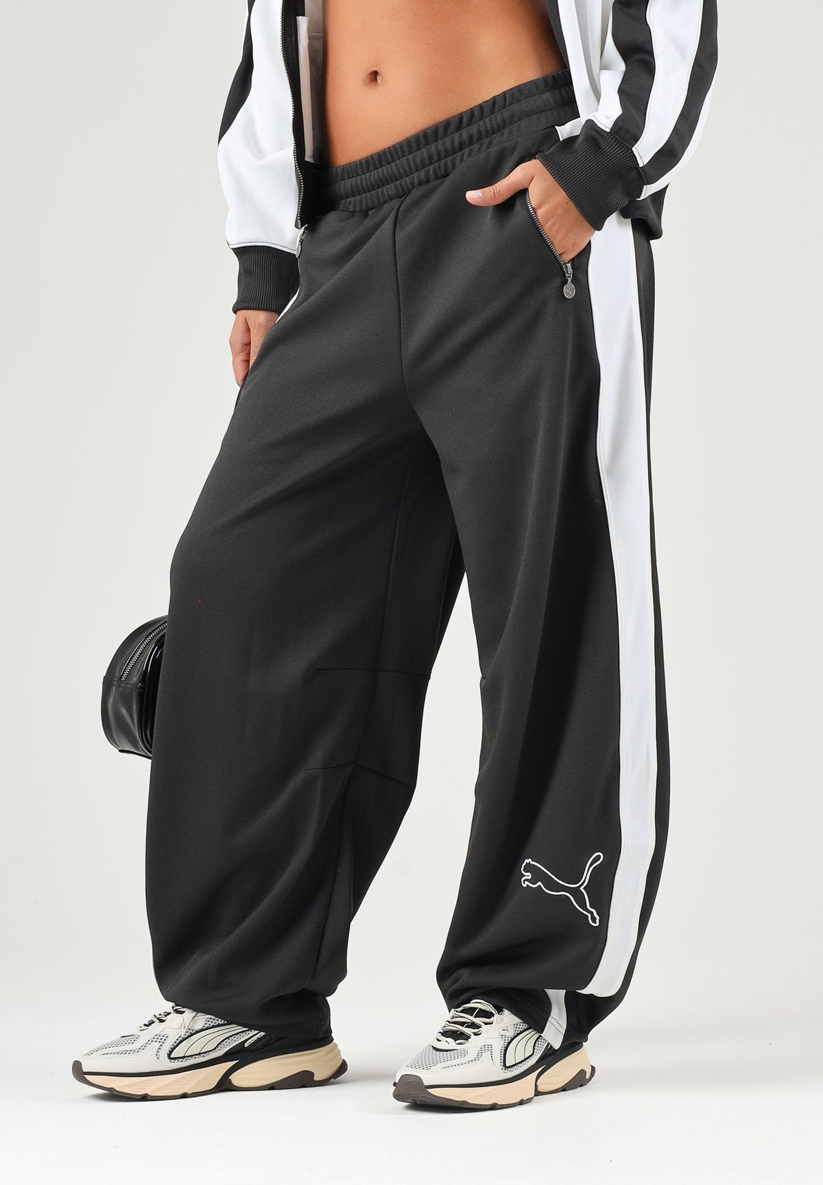 PUMA Pantalone DARE TO WOVEN nero per donna con bande laterali bianche, tasche zippate e gamba ampia. 636633 01 PUMA