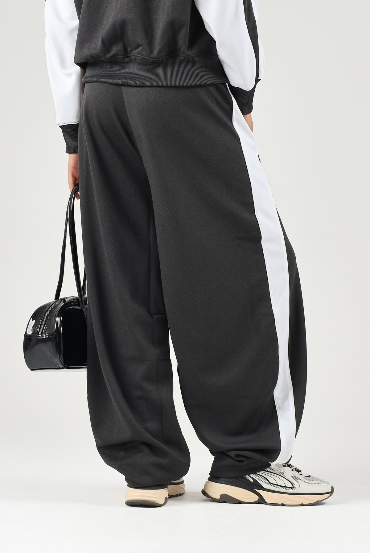 PUMA Pantalone DARE TO WOVEN nero per donna con bande laterali bianche, tasche zippate e gamba ampia. 636633 01 PUMA