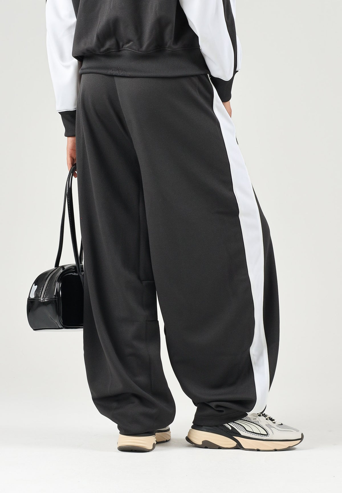 PUMA Pantalone DARE TO WOVEN nero per donna con bande laterali bianche, tasche zippate e gamba ampia. 636633 01 PUMA