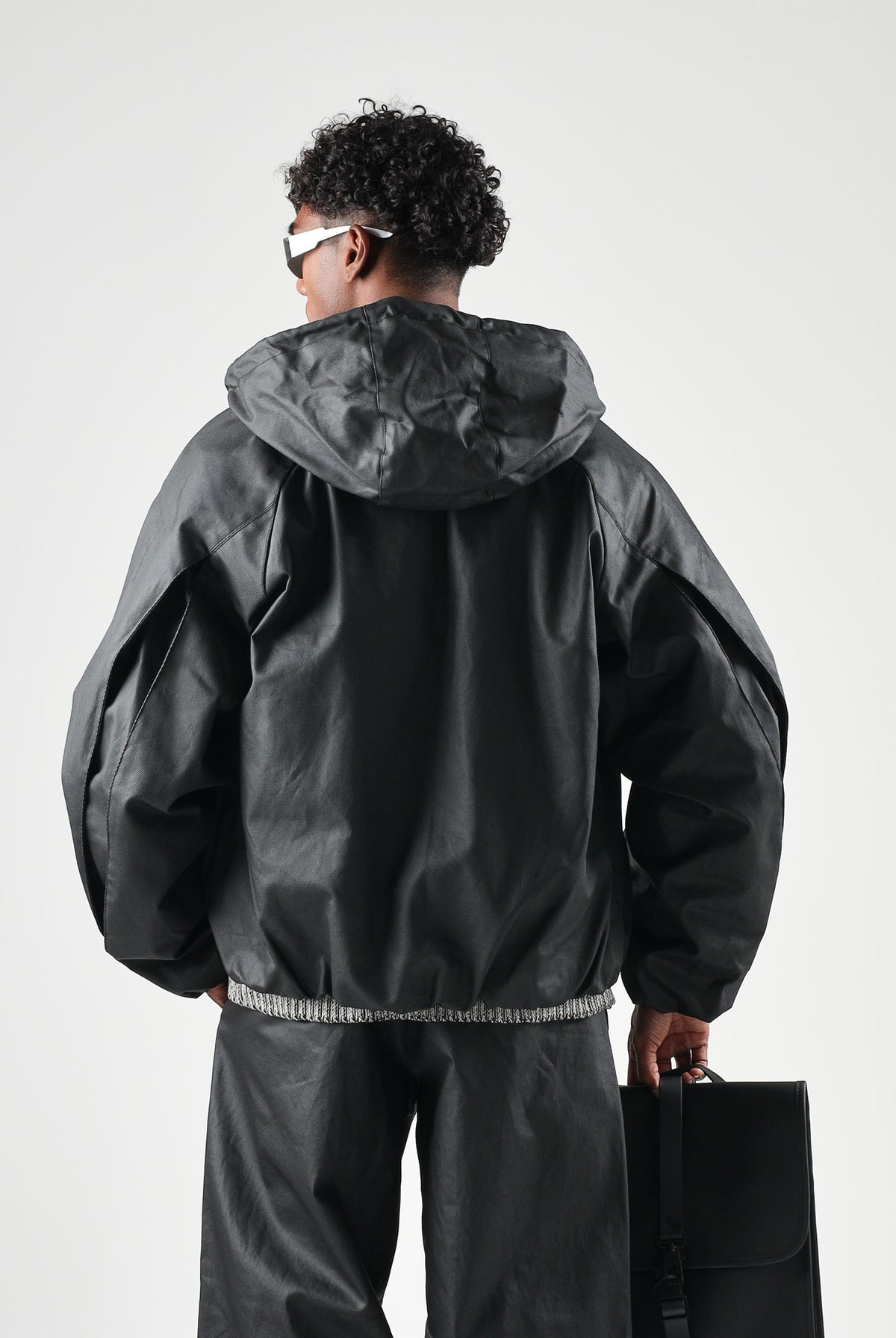 RAINS Giubbotto in eco-pelle HEAVY WOVEN JACKET nero per uomo e donna con cappuccio e maniche con pieghe strutturate RA19230 BL RAINS