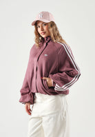ADIDAS ORIGINALS Felpa con zip ADILENIUM SEASON 6 FAUX SUEDE TRACK TOP Maroon bordeaux scuro da donna in tessuto spacer effetto scamosciato sintetico, con collo alto, zip frontale integrale, tre strisce sulle maniche e logo Trifoglio sul petto. LH1920 . ADIDAS ORIGINALS 