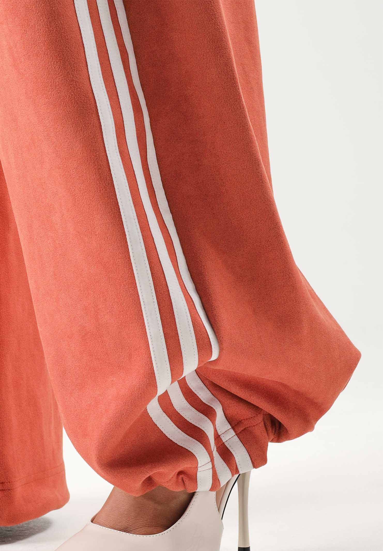 ADIDAS ORIGINALS Pantaloni ADILENIUM SEASON 6 FAUX SUEDE TRACK PANT arancione terracotta da donna, in tessuto effetto camoscio sintetico, con tre strisce laterali a contrasto e gamba ampia. LH1926 . ADIDAS ORIGINALS 