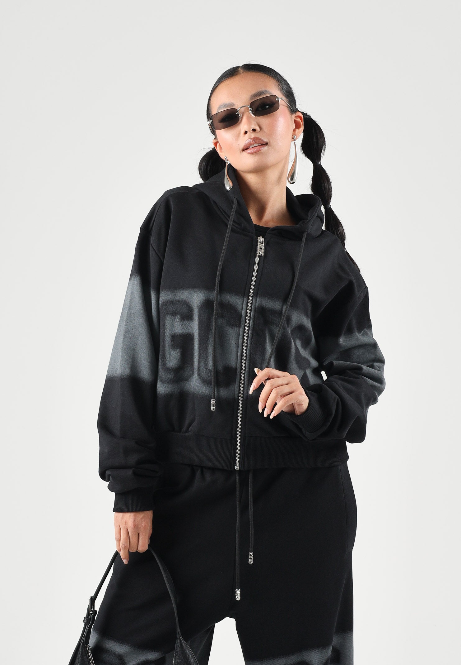 GCDS Felpa con cappuccio e zip SPRAY LOGO Black-Grey nera e grigia da donna, in puro cotone heavy fleece, con maxi stampa GCDS effetto spray sul davanti, fascia orizzontale a contrasto e tasche a marsupio. C2WWQE228F034 999I GCDS 