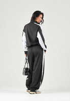 PUMA Pantalone DARE TO WOVEN nero per donna con bande laterali bianche, tasche zippate e gamba ampia. 636633 01 PUMA 