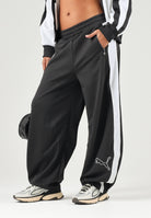 PUMA Pantalone DARE TO WOVEN nero per donna con bande laterali bianche, tasche zippate e gamba ampia. 636633 01 PUMA 