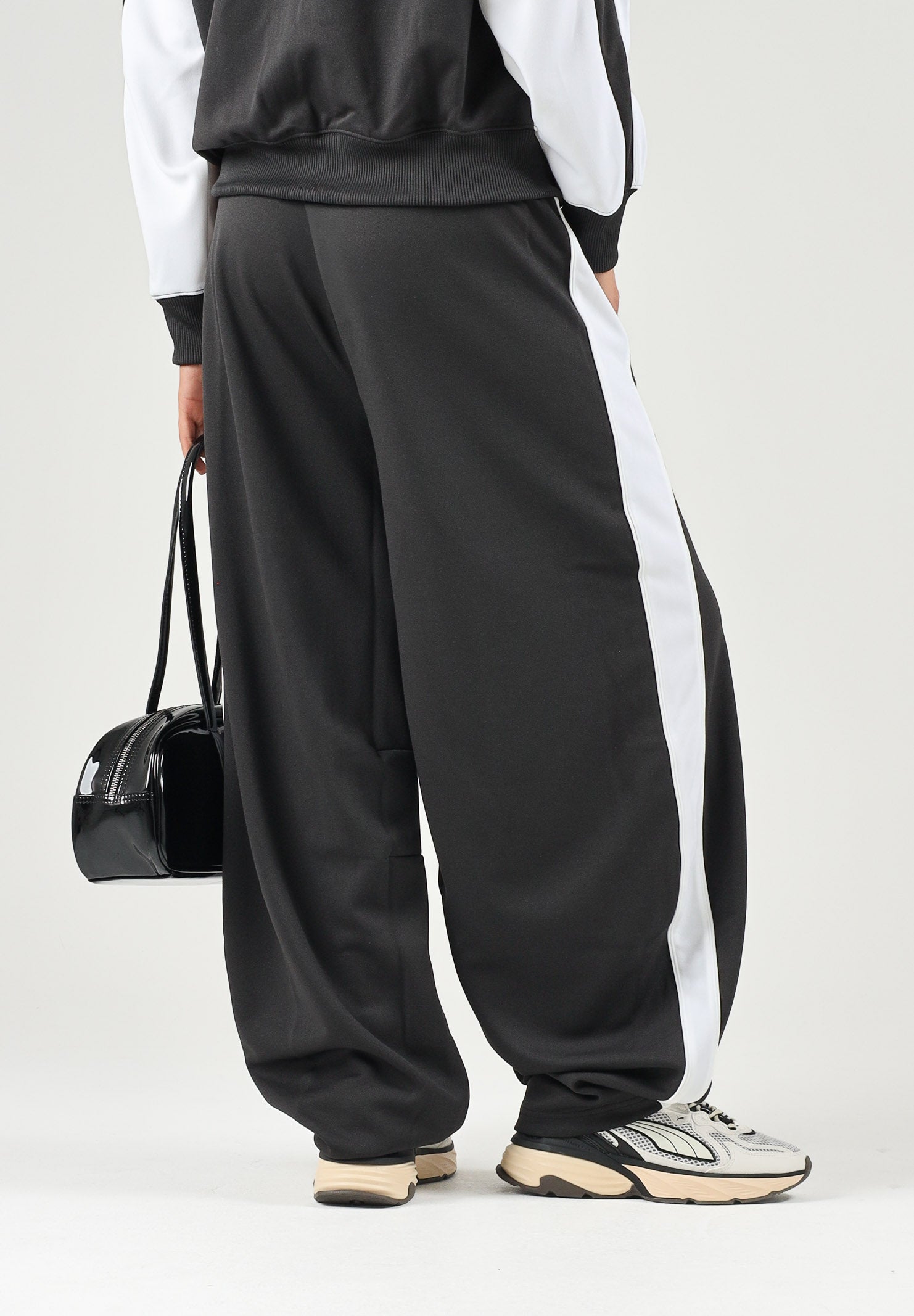 PUMA Pantalone DARE TO WOVEN nero per donna con bande laterali bianche, tasche zippate e gamba ampia. 636633 01 PUMA 