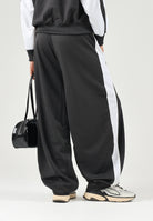 PUMA Pantalone DARE TO WOVEN nero per donna con bande laterali bianche, tasche zippate e gamba ampia. 636633 01 PUMA 