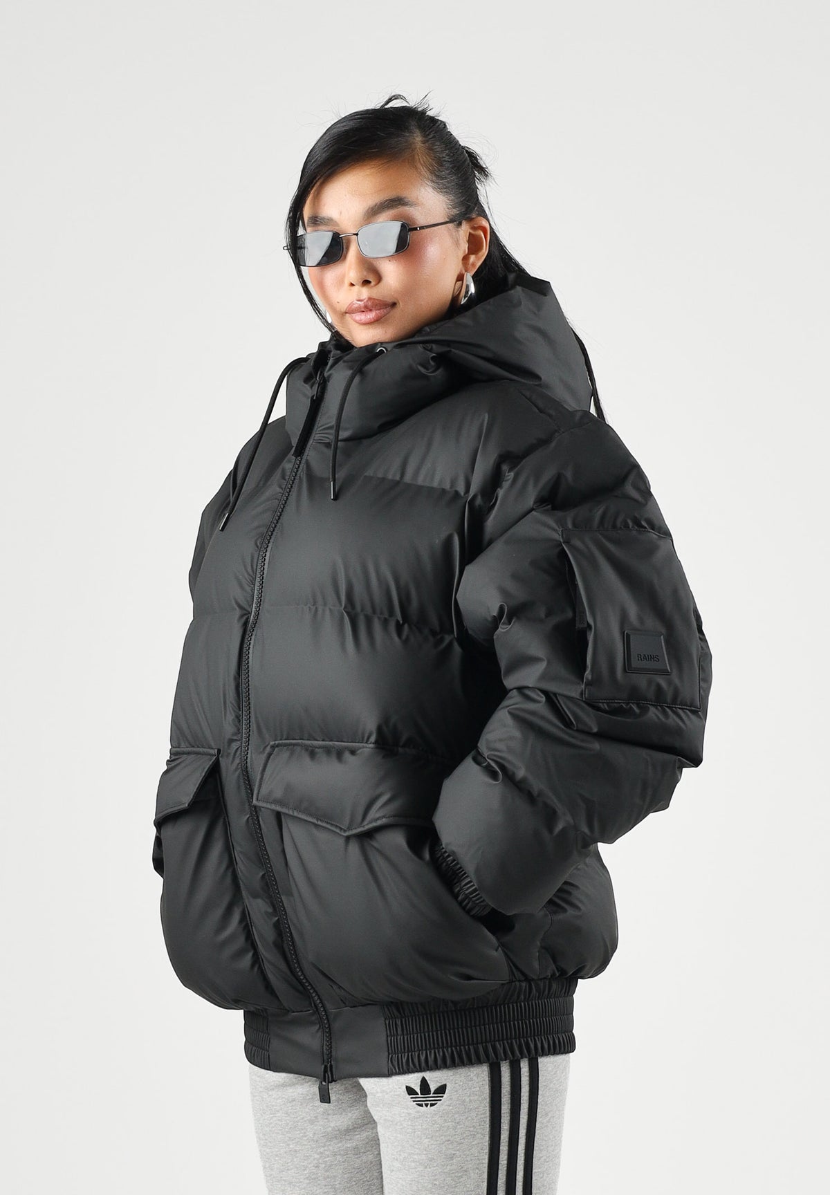 RAINS Piumino nero per uomo e donna con cappuccio regolabile e chiusura full zip impermeabile. RA16990 BL RAINS 