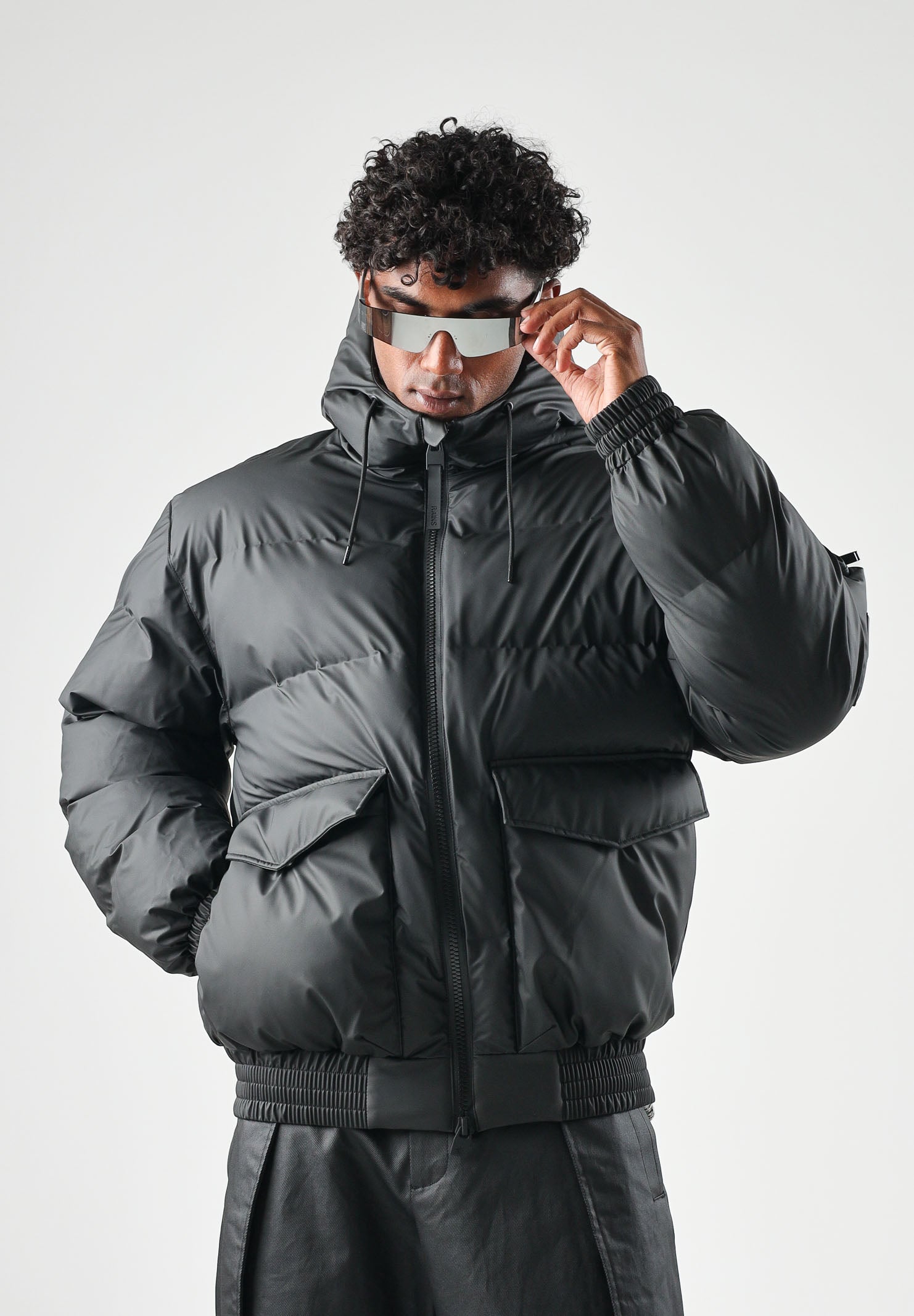 RAINS Piumino nero per uomo e donna con cappuccio regolabile e chiusura full zip impermeabile. RA16990 BL RAINS 