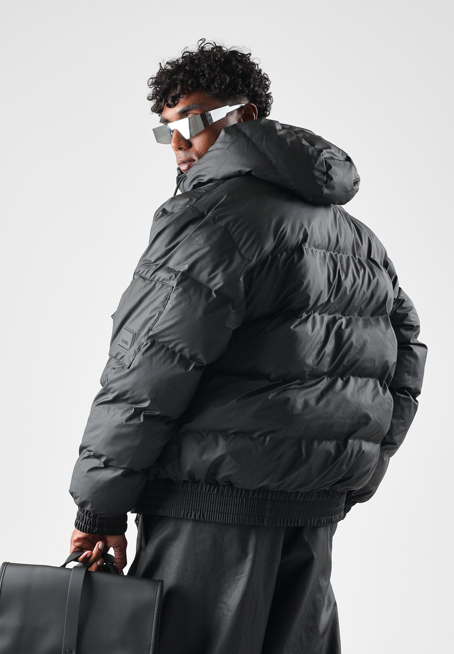 RAINS Piumino nero per uomo e donna con cappuccio regolabile e chiusura full zip impermeabile. RA16990 BL RAINS 