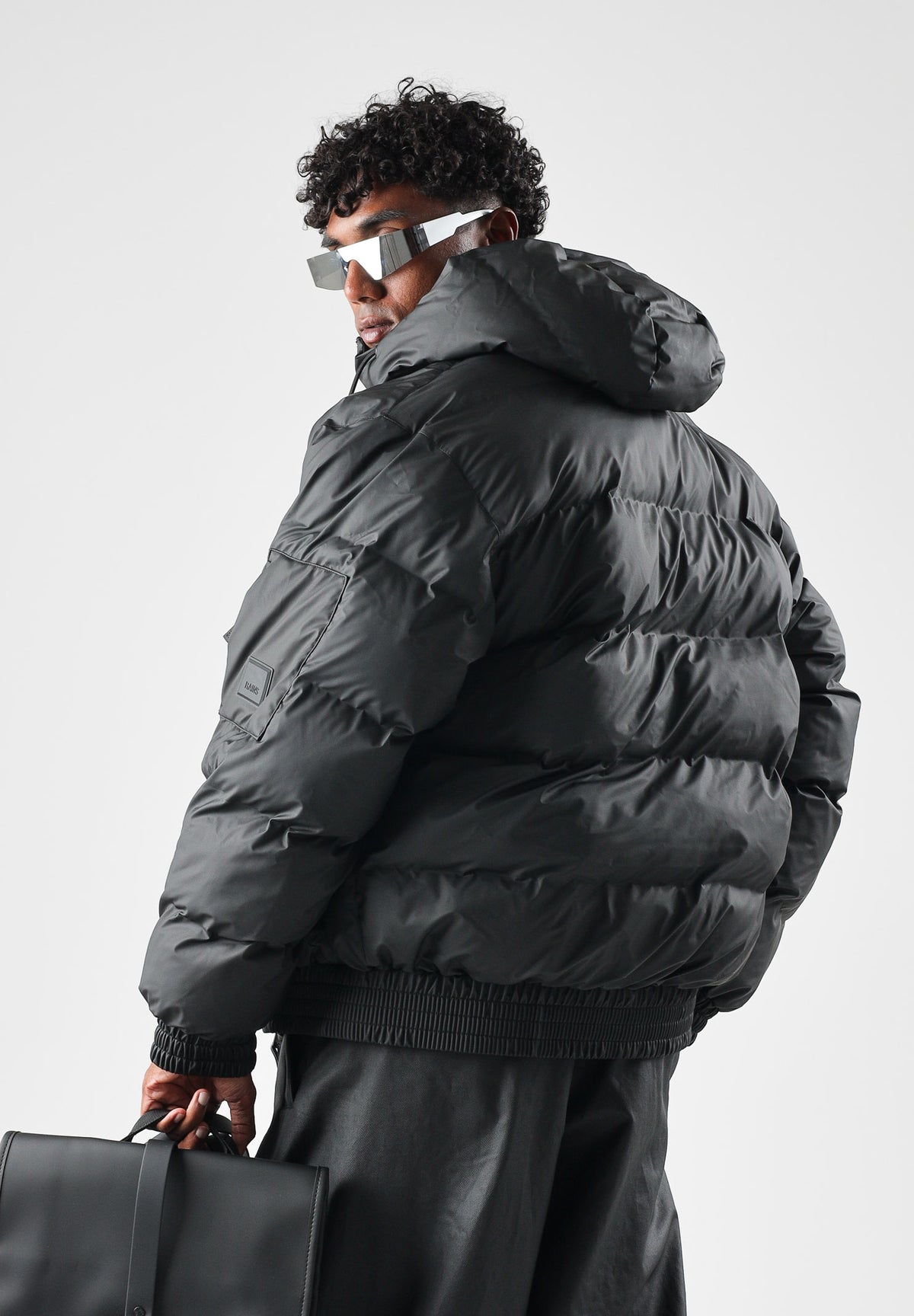 RAINS Piumino nero per uomo e donna con cappuccio regolabile e chiusura full zip impermeabile. RA16990 BL RAINS 