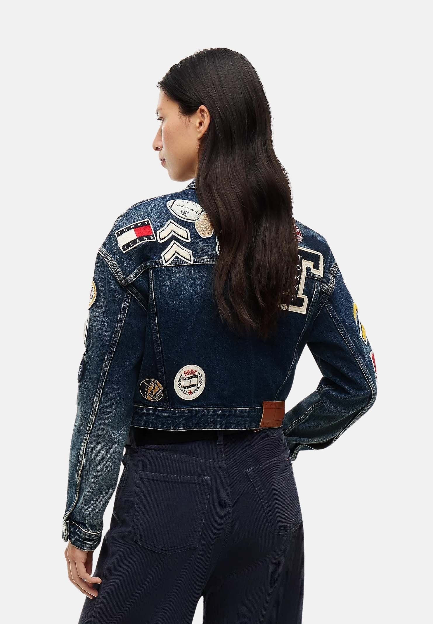 TOMMY JEANS Giacca in denim TOMMY BADGE CROPPED DENIM TRUCKER  blu scuro da donna chiusura frontale con bottoni, maniche lunghe e applicazioni decorative multicolore in stile varsity.<BR/> DW0DW23242 1BK TOMMY JEANS 