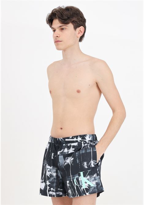 Shorts mare nero da uomo con stampa di palme e maxi logo monogram CALVIN KLEIN | Beachwear | KM0KM009680GL