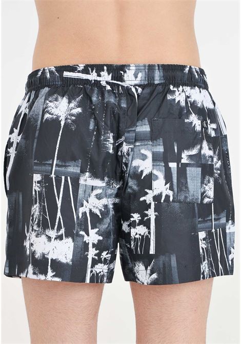 Shorts mare nero da uomo con stampa di palme e maxi logo monogram CALVIN KLEIN | Beachwear | KM0KM009680GL
